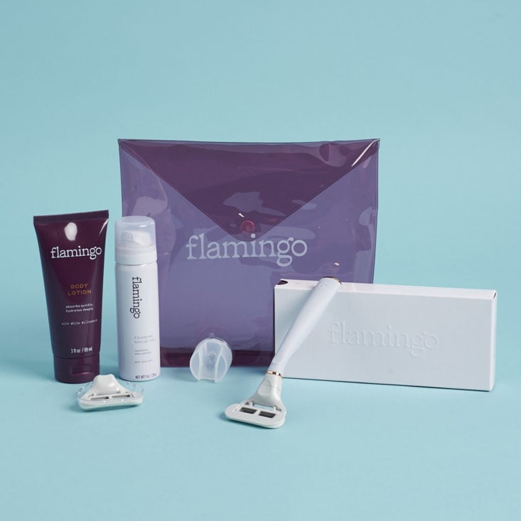 Flamingo starter kit including taro handle, 2 cartridges, body lotion, shave foam, suction cup holder, and a purple carry pouch on a blue background
