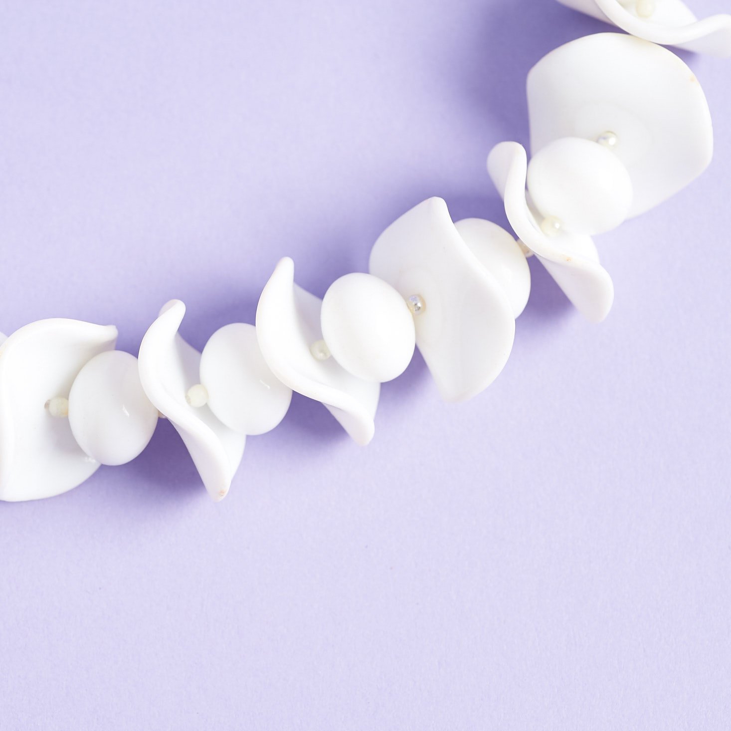 Close up on the white round and shell-shaped beads of this necklace