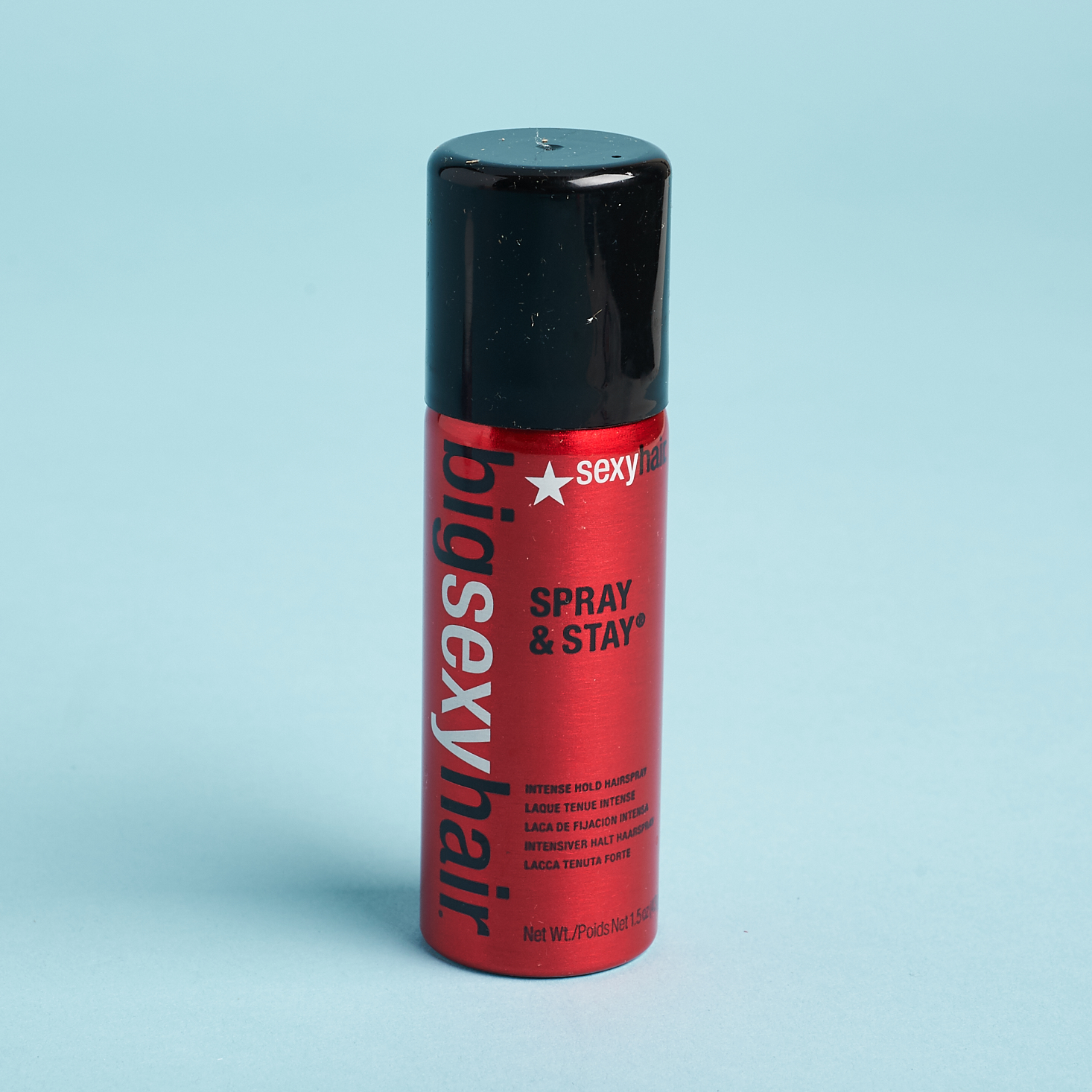 red bottle of hair spray with black cap