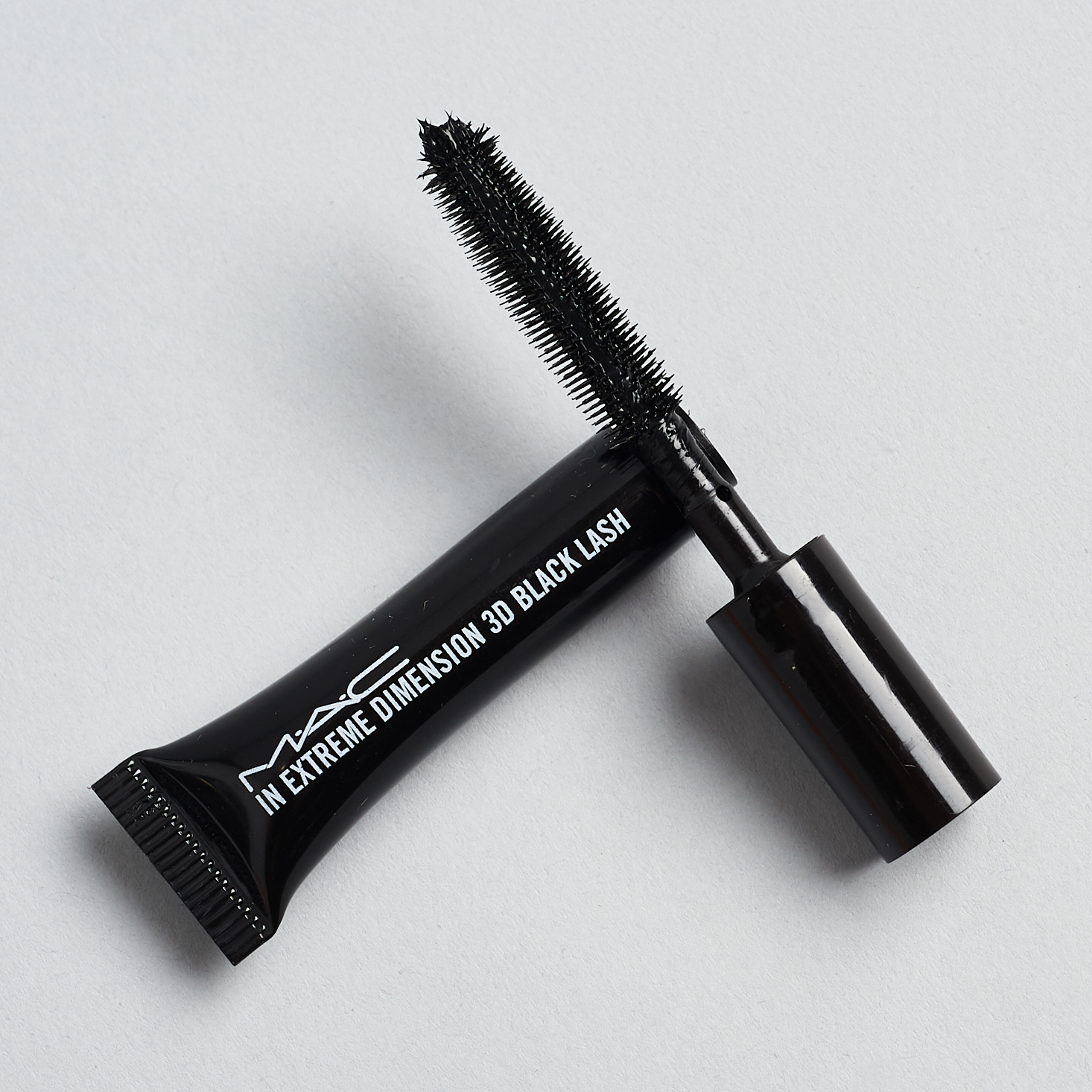 Opened MAC Cosmetics In Extreme Dimension 3D Black Lash Mascara with wand resting on tube