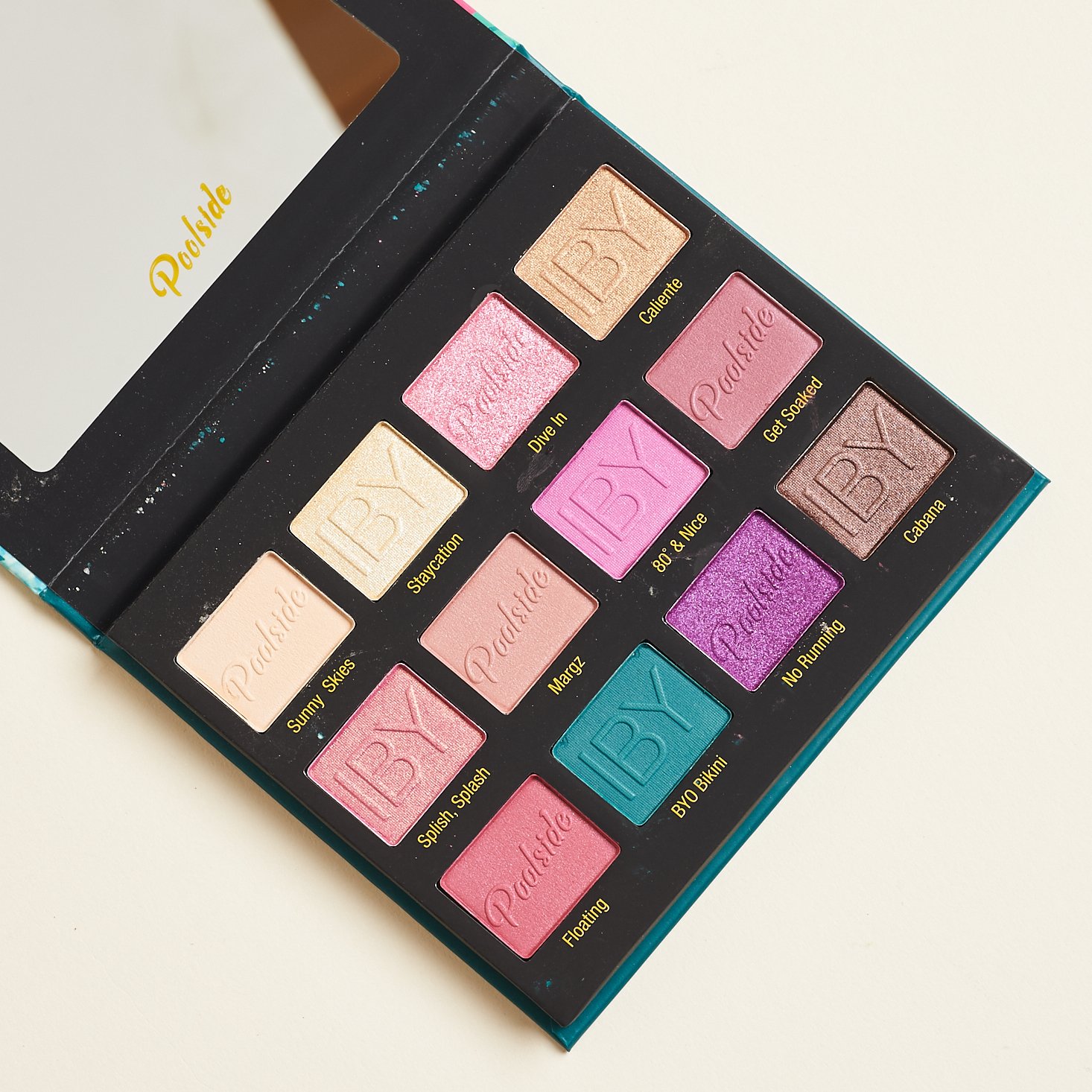 inside of the eyeshadow palette showing 12 shades ranging from ivory, to pink and purple, and teal