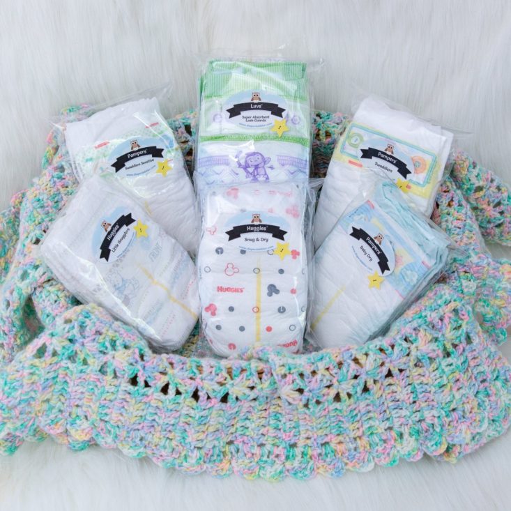 a sample assortment of diaper dabbler diapers sitting in a pastel crocheted blanket