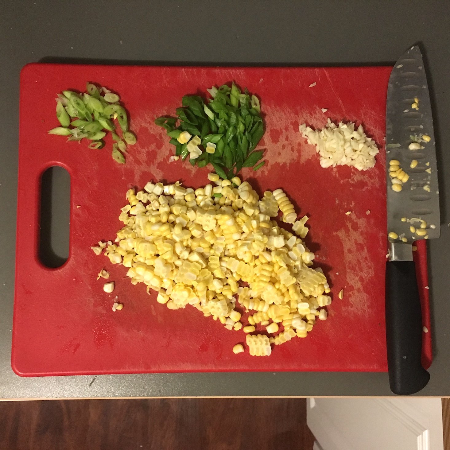 cajun shrimp and corn pancakes chopped corn, green onions, and garlic on a cutting board