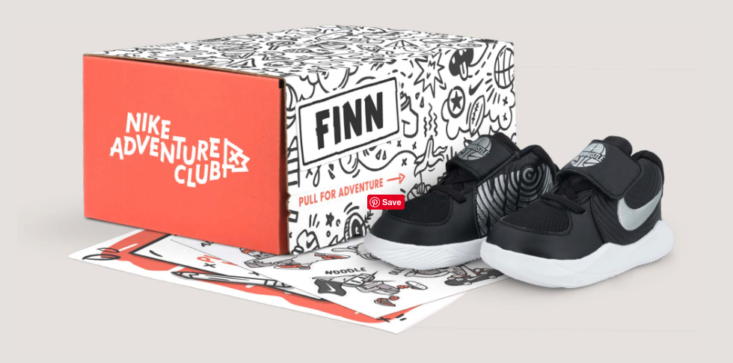 Black Nike sneakers with silver swoosh for kids from the Nike Adventure Club box.
