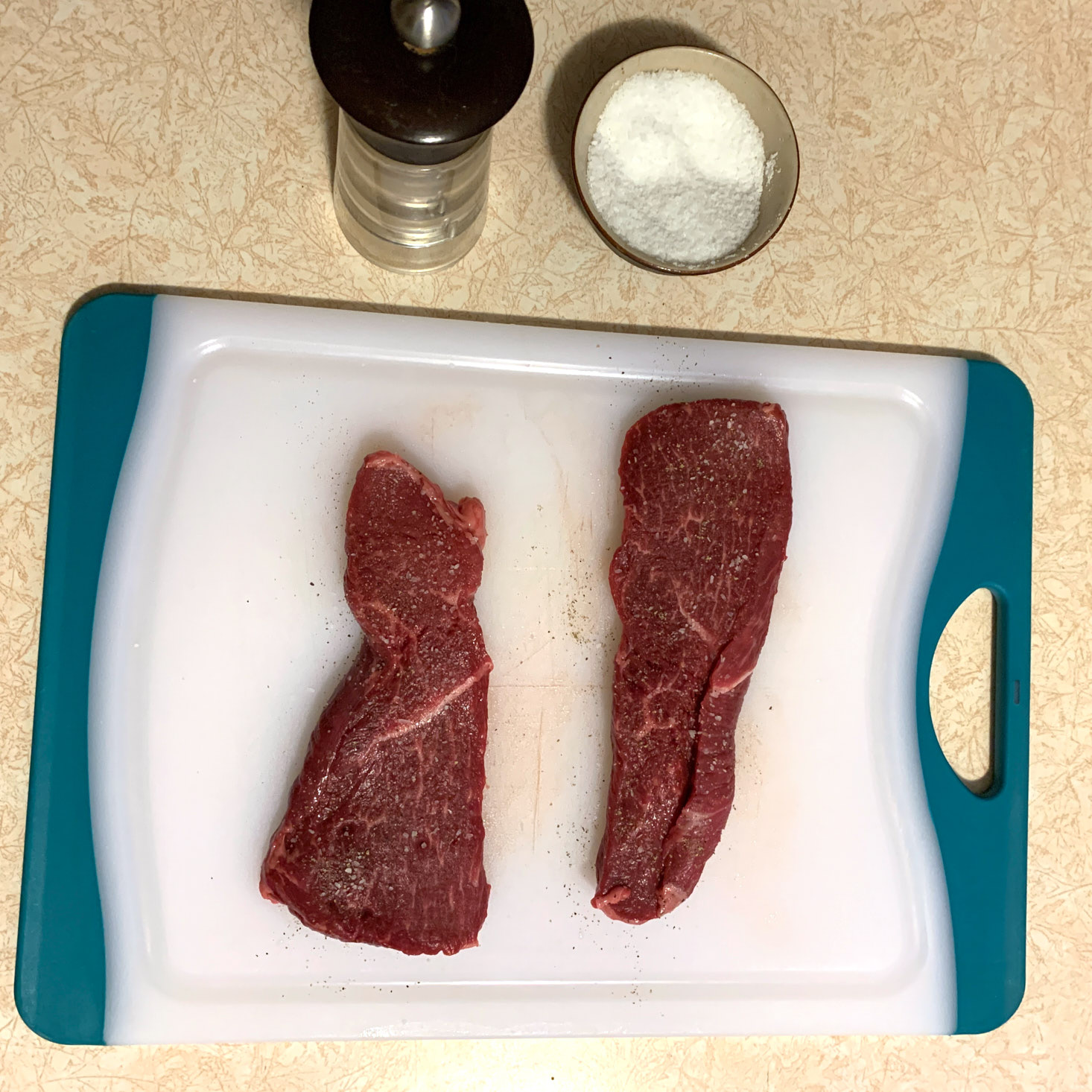 steak on cutting board with salt + pepper