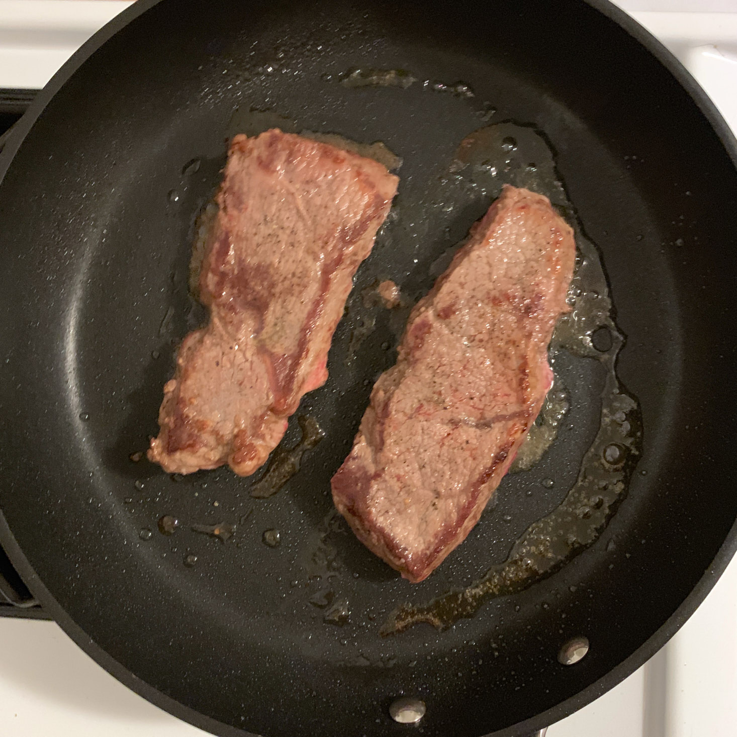 steaks cooking in a pan