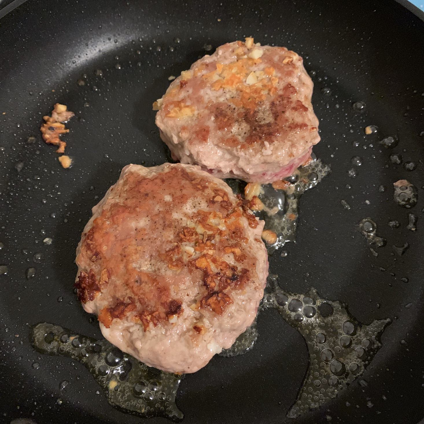 Pork burgers cooking in pan