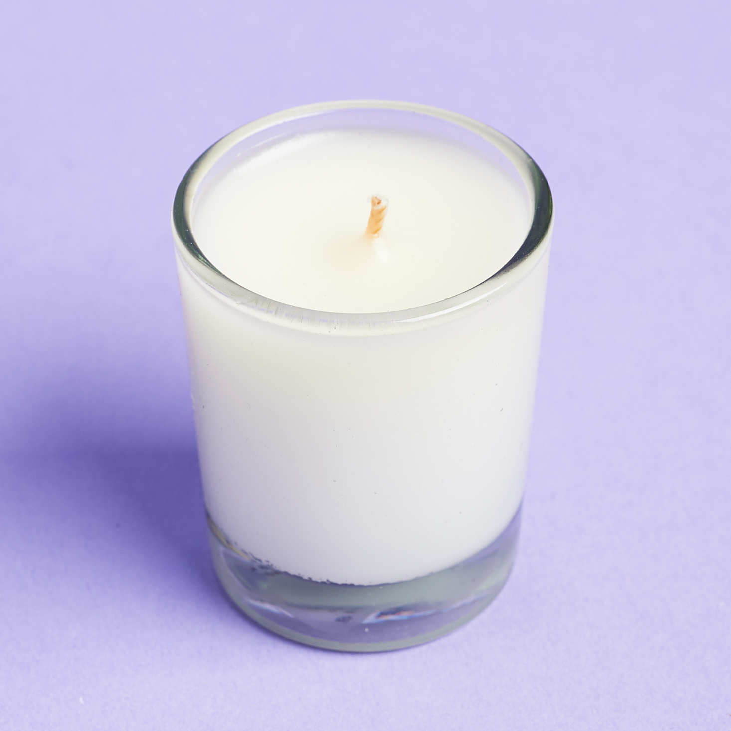 white wax candle in small glass votice