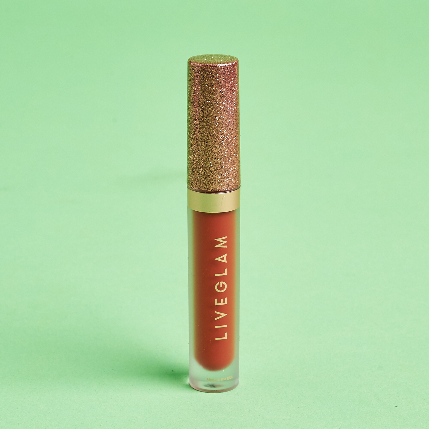 rose gold glitter cap on frosted tube of burnt orange lipstick
