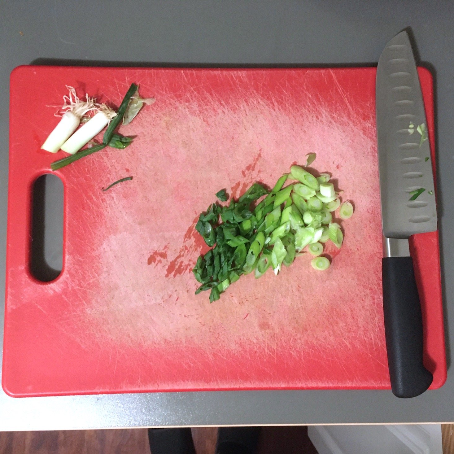 green onions chopped on a red cutting board