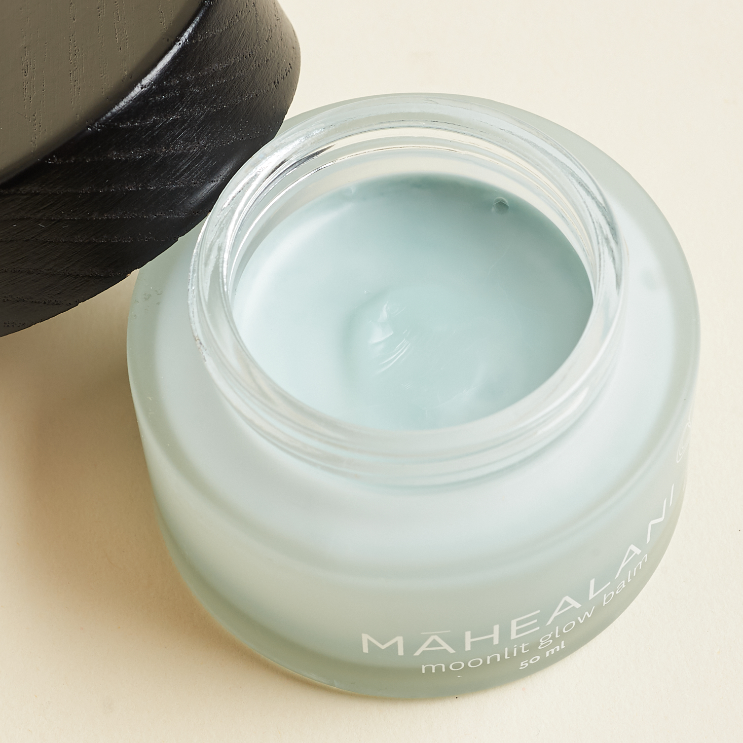 opened Honua Skincare Mahealani Moonlit Glow Balm, with cap leaning on edge