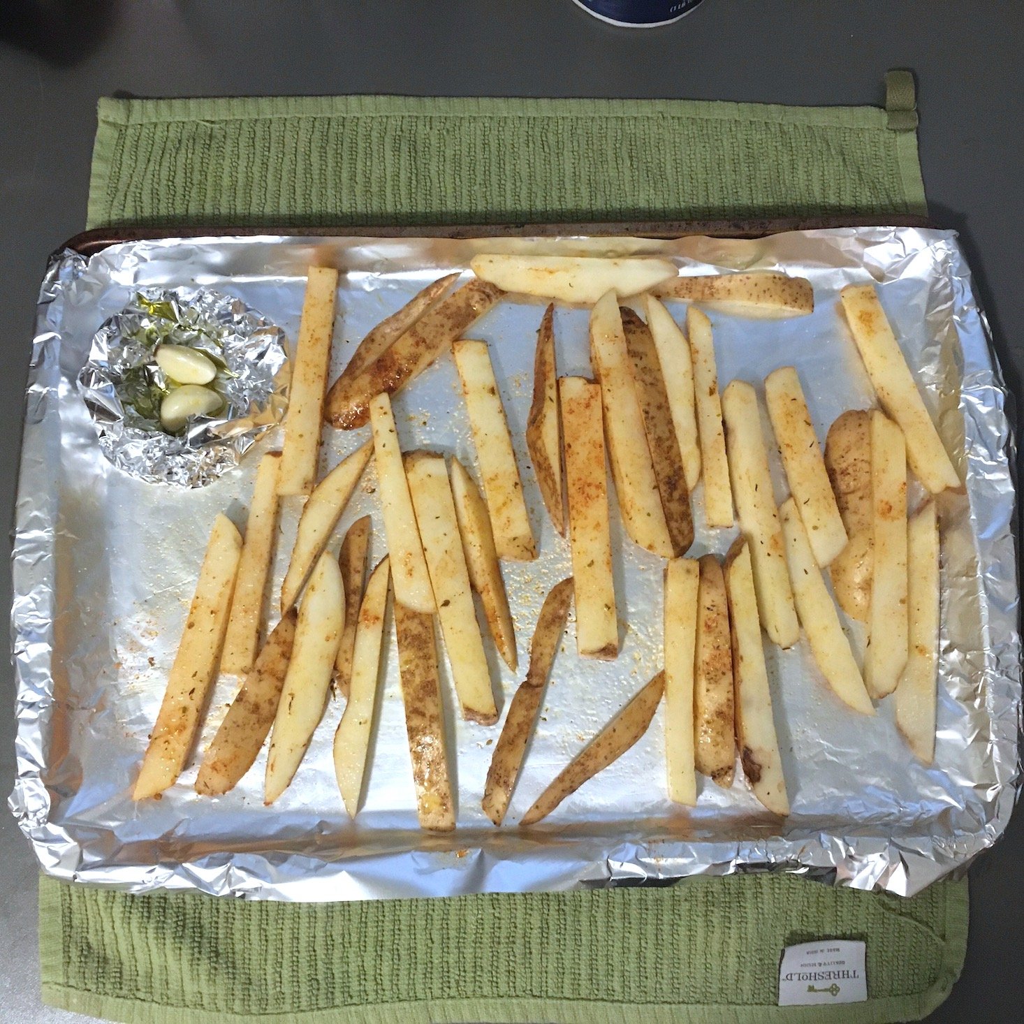 shrimp sandwich cut fries tossed in seasoning on a baking sheet with garlic