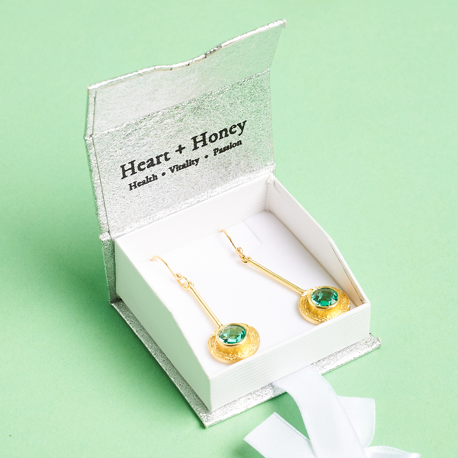 open box showing gold and green earrings inside