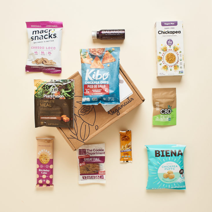 A bird's eye view of various snacks vertically lined up with a Vegancuts box in the center.