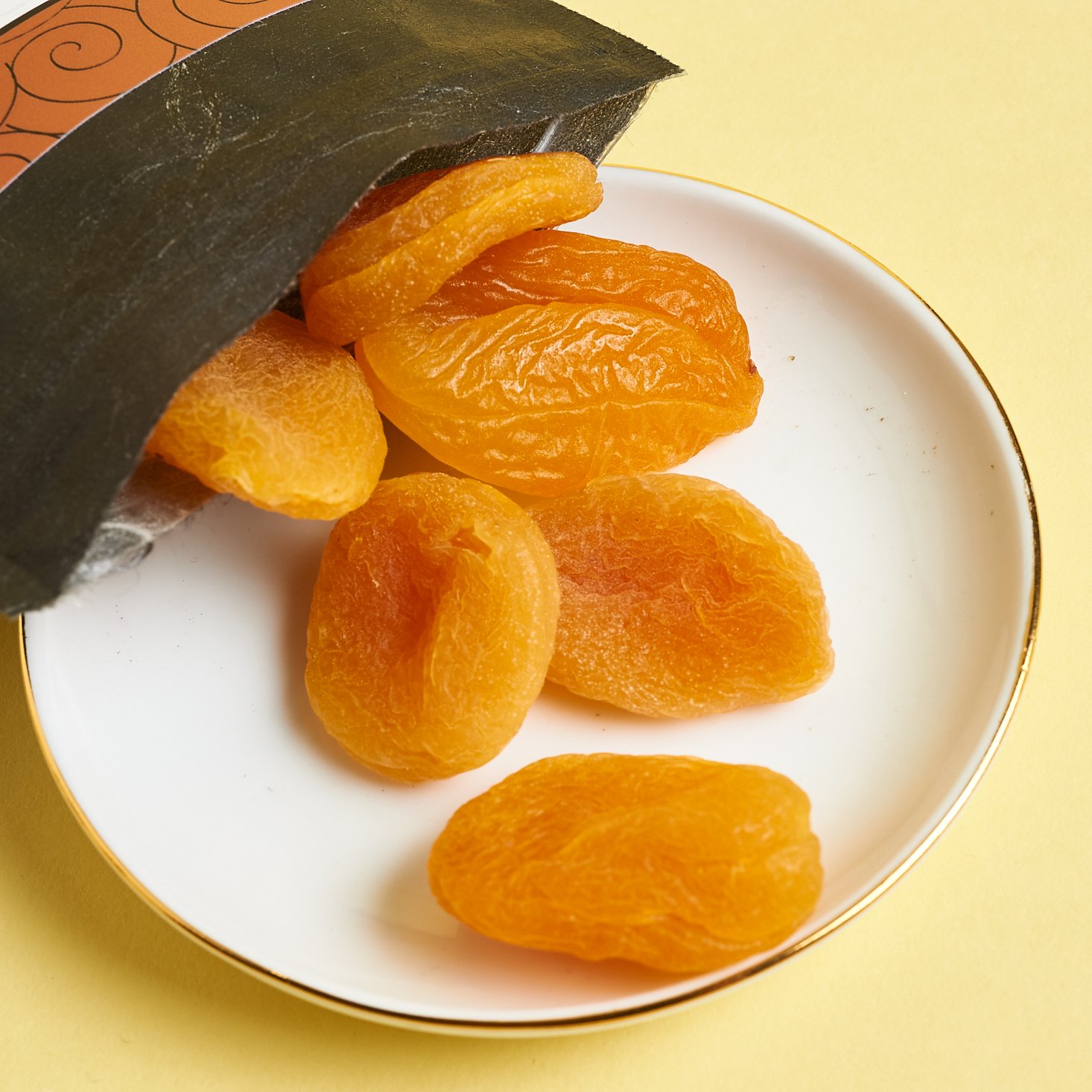 An open bag of dried apricots spilling onto a plate