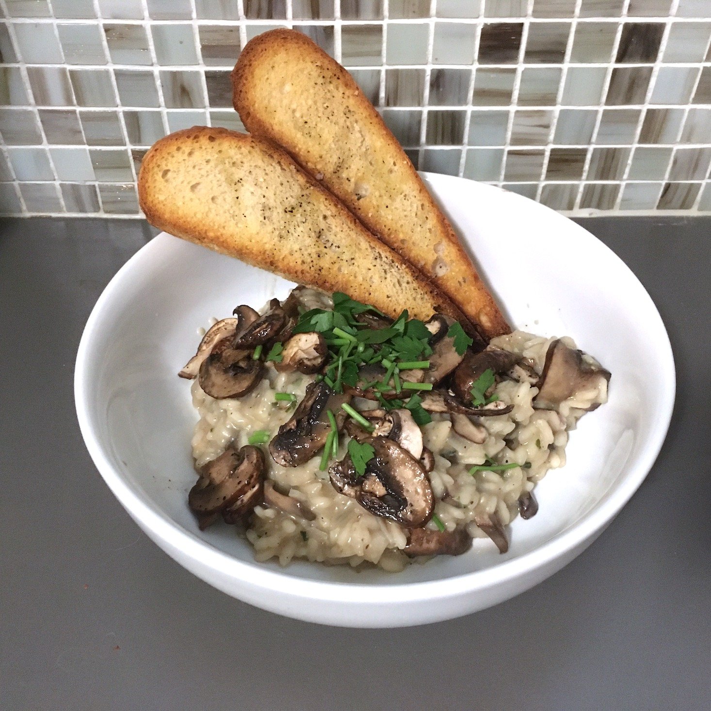 mushroom risotto plated against tile backdrop