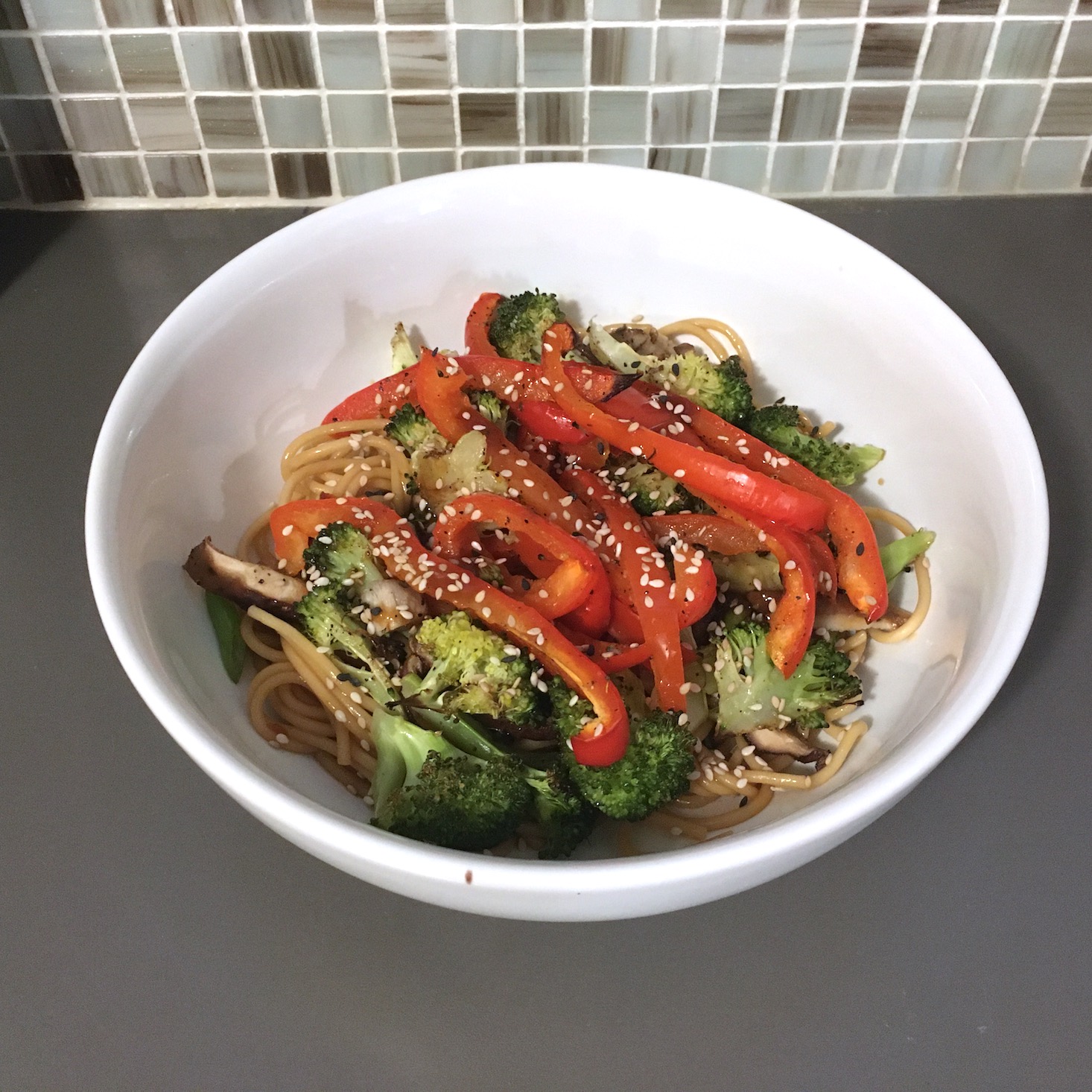 teriyaki noodles plated against tile backdrop