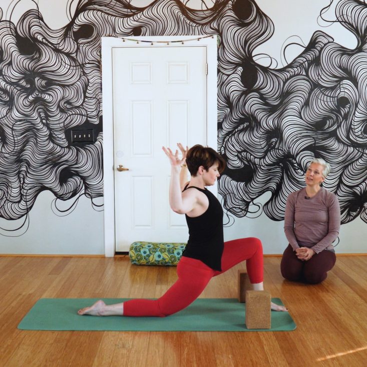 Yoga teacher guiding student.