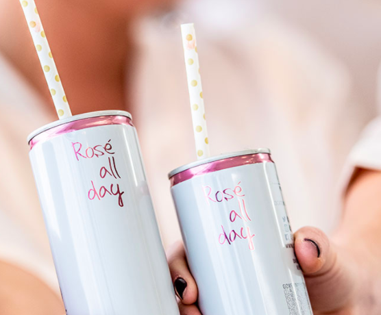 Rosé All Day cans with straws in them.