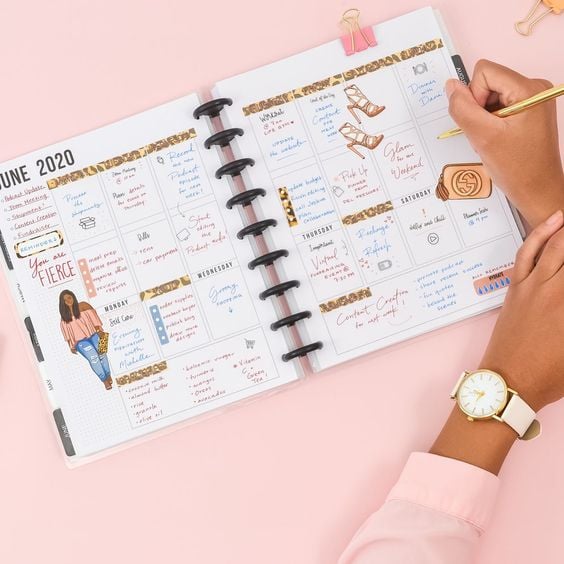 Woman's hands writing in a decked out planner.