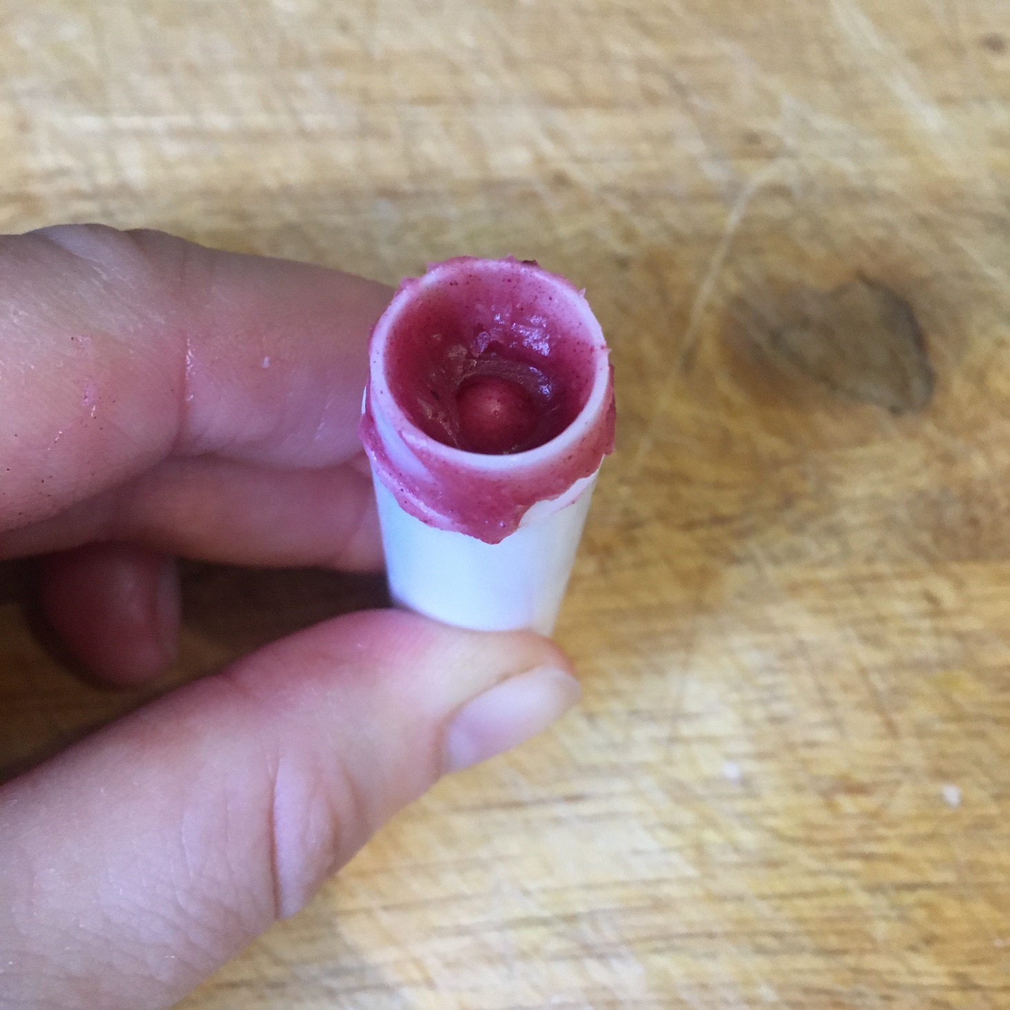 Tapping the container to help the lip balm reach the bottom.