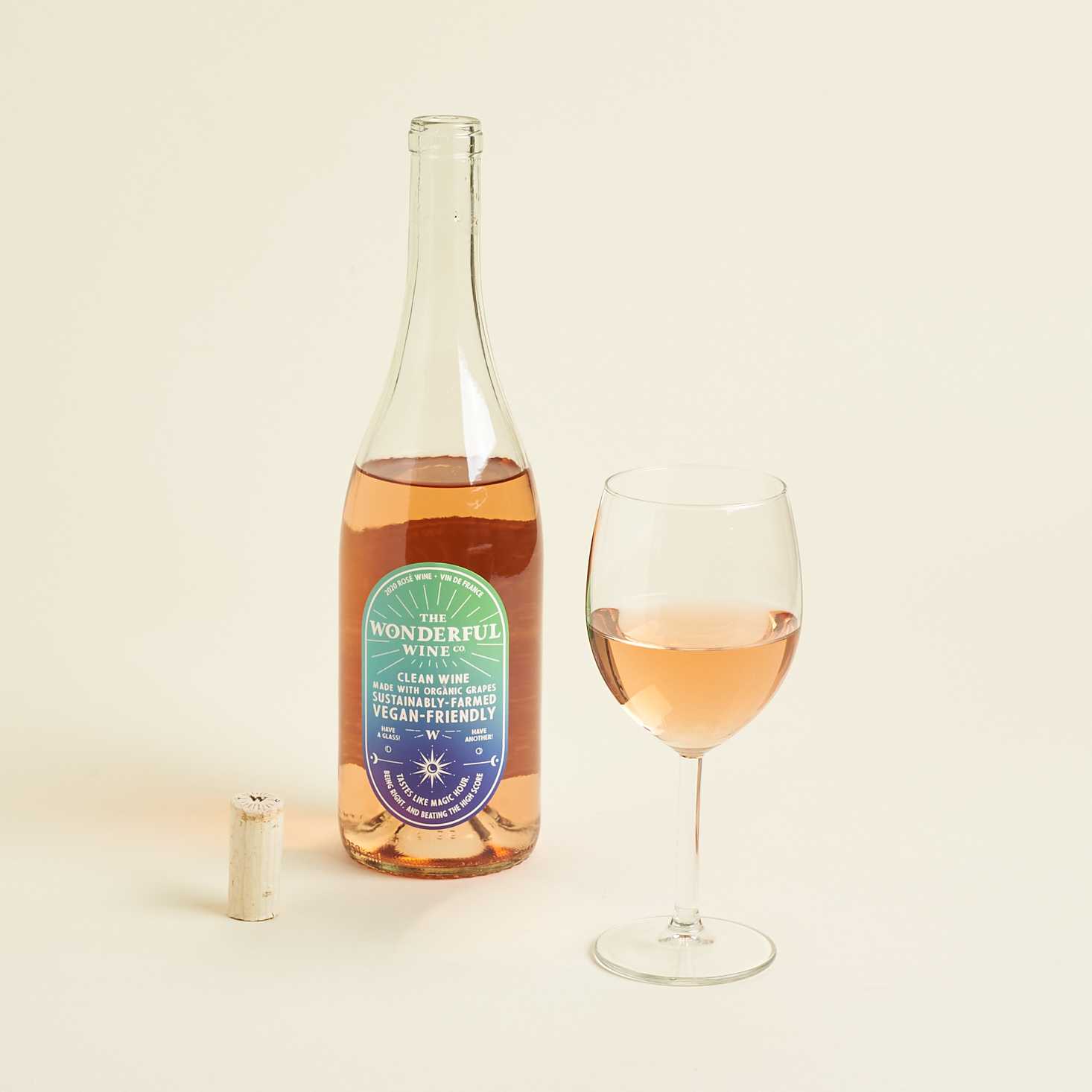 filled glass of wine beside open bottle and cork