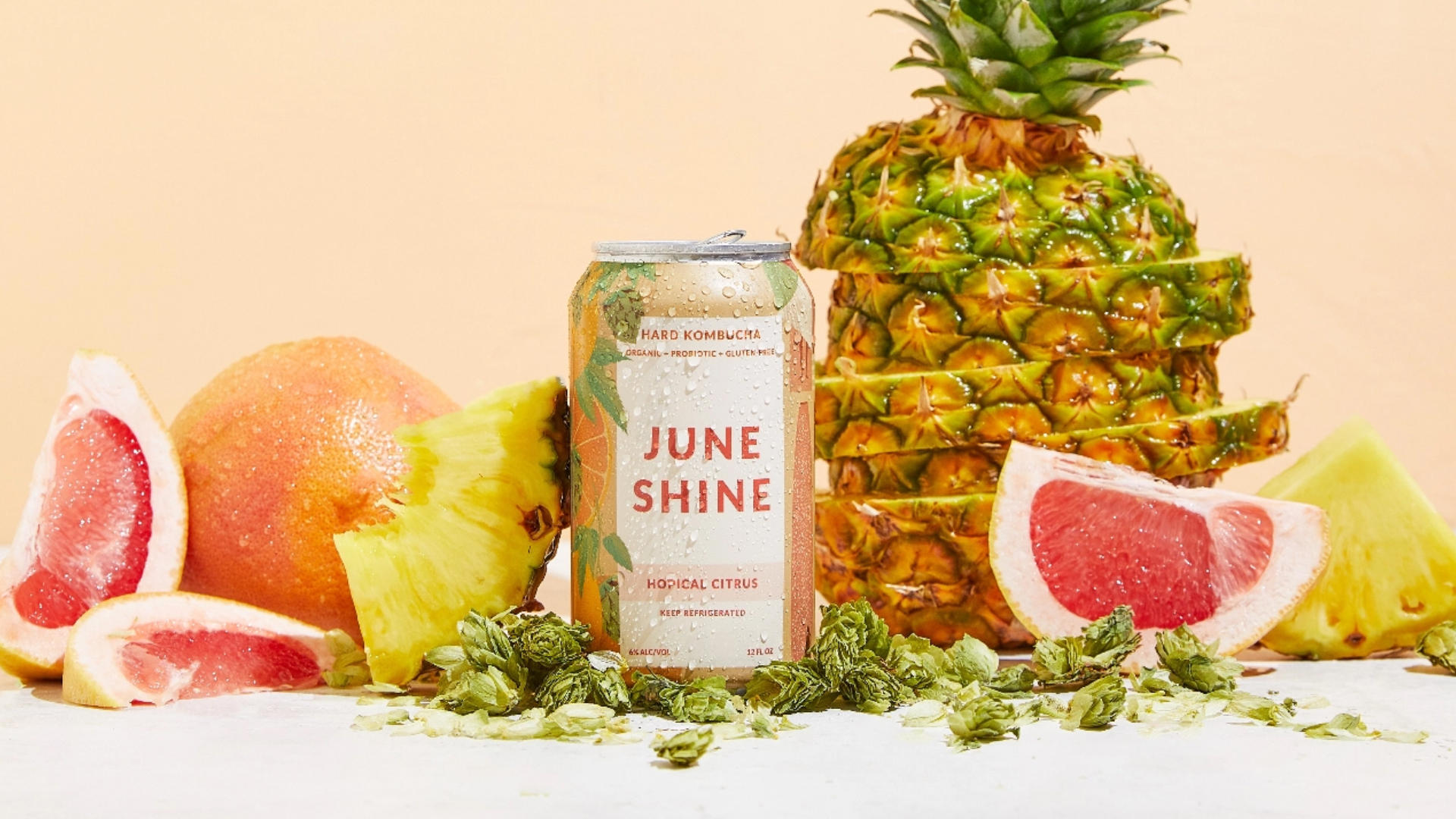 can of June Shine beside sliced pineapple and fruits