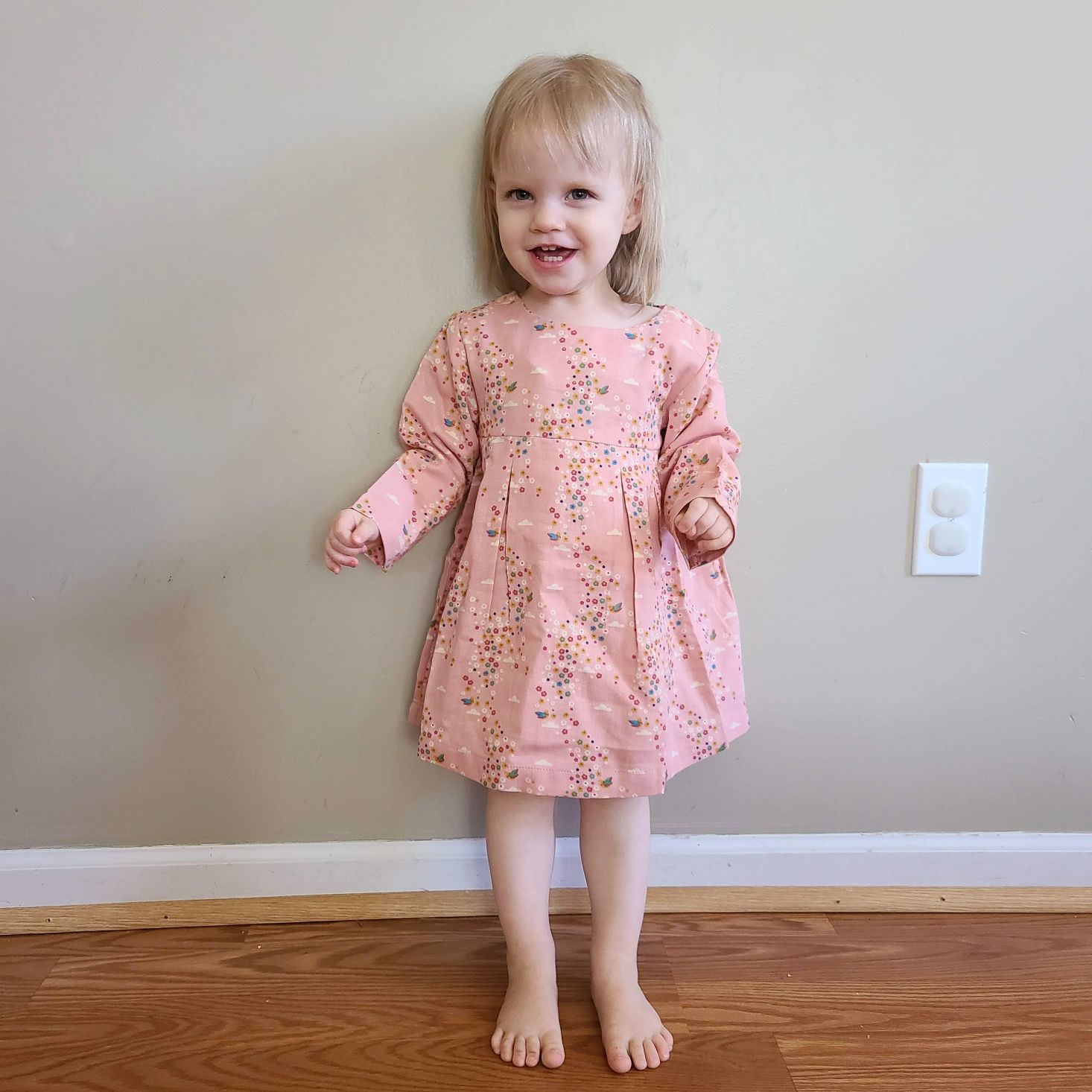 Pink floral smock dress from Little Green Radicals modeled on toddler