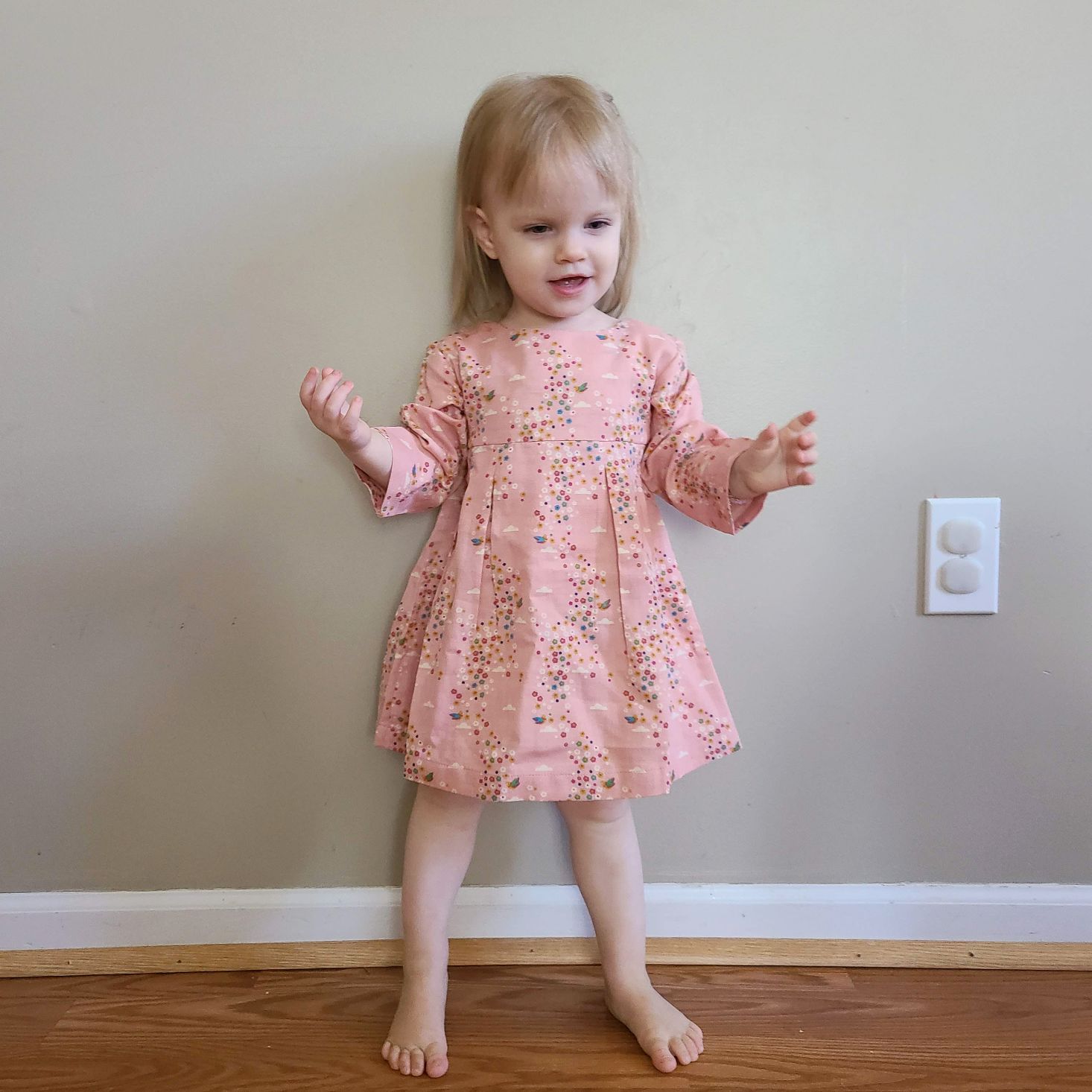 Pink floral smock dress from Little Green Radicals modeled on toddler