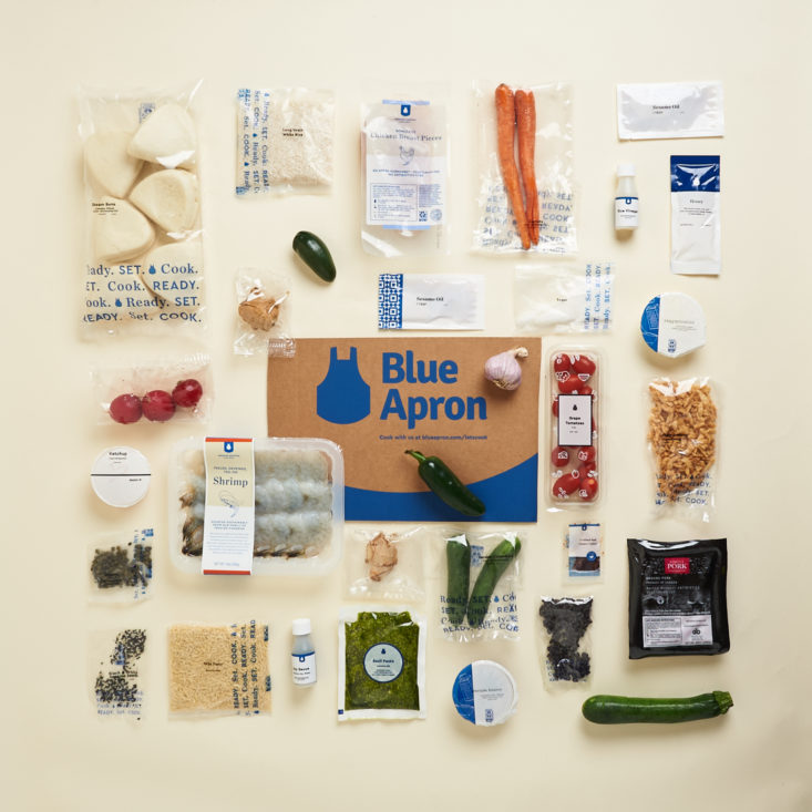 blue apron box with food all around it 