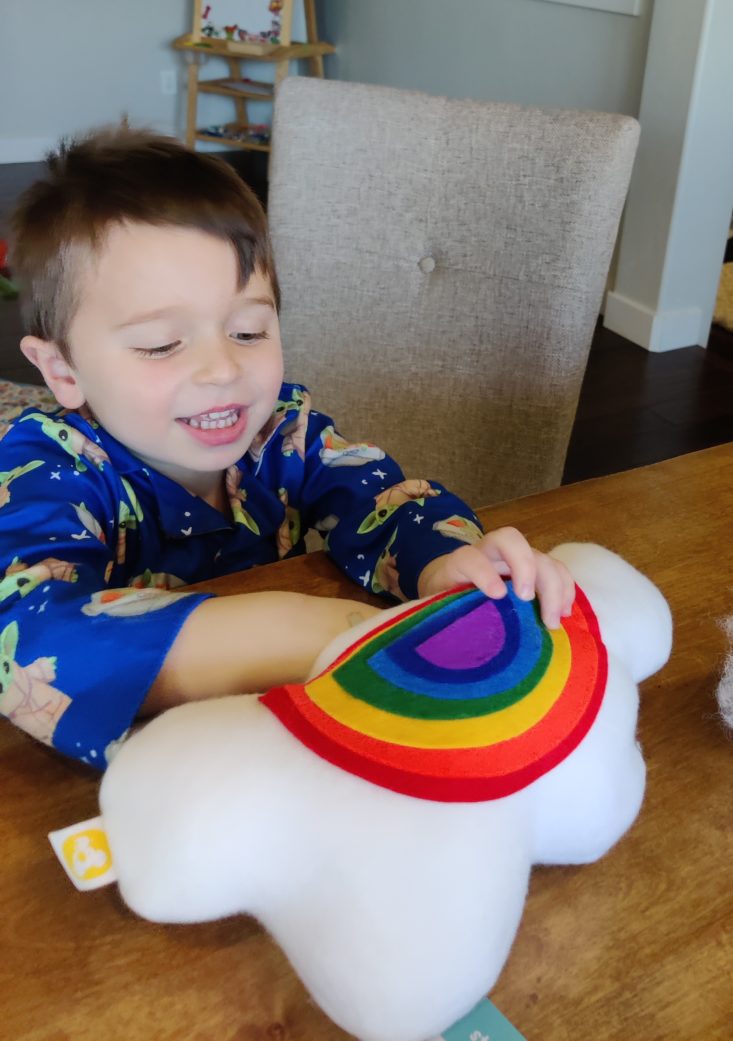 Happy boy making a stuffed rainbow from a KiwiCo project