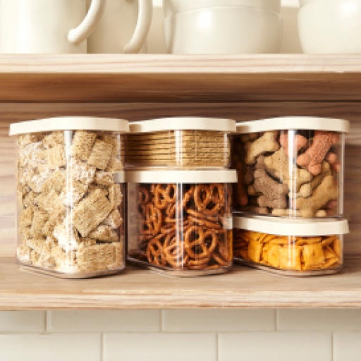 five plastic pantry containers filled with pretzels, dog treats, goldfish, and other pantry staples