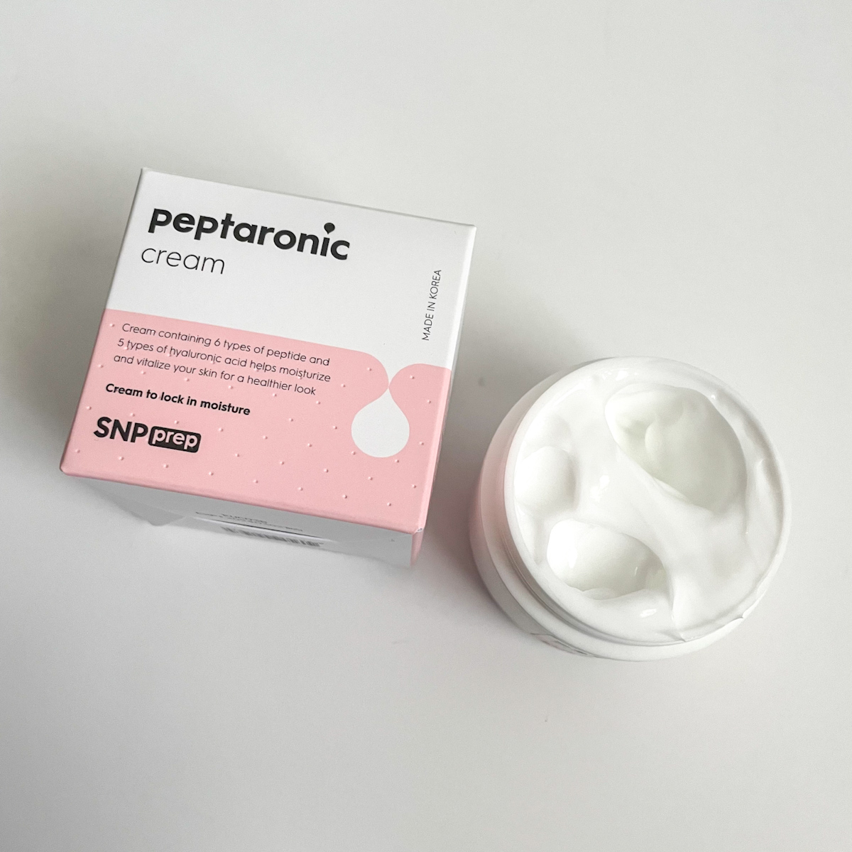 pink and white packaging with white texture of moisturizer