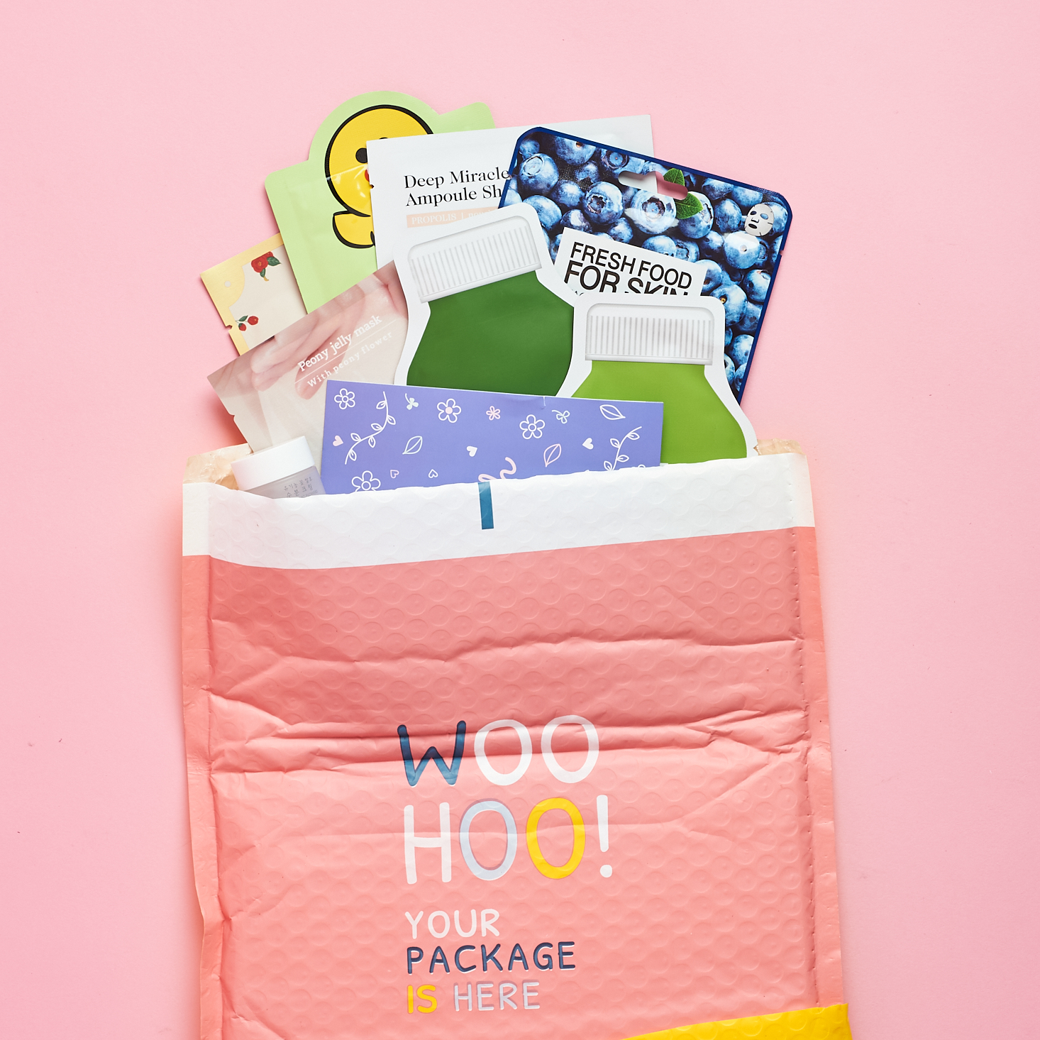pink bubble mailer packaging opened at the top with sheet masks peeking out