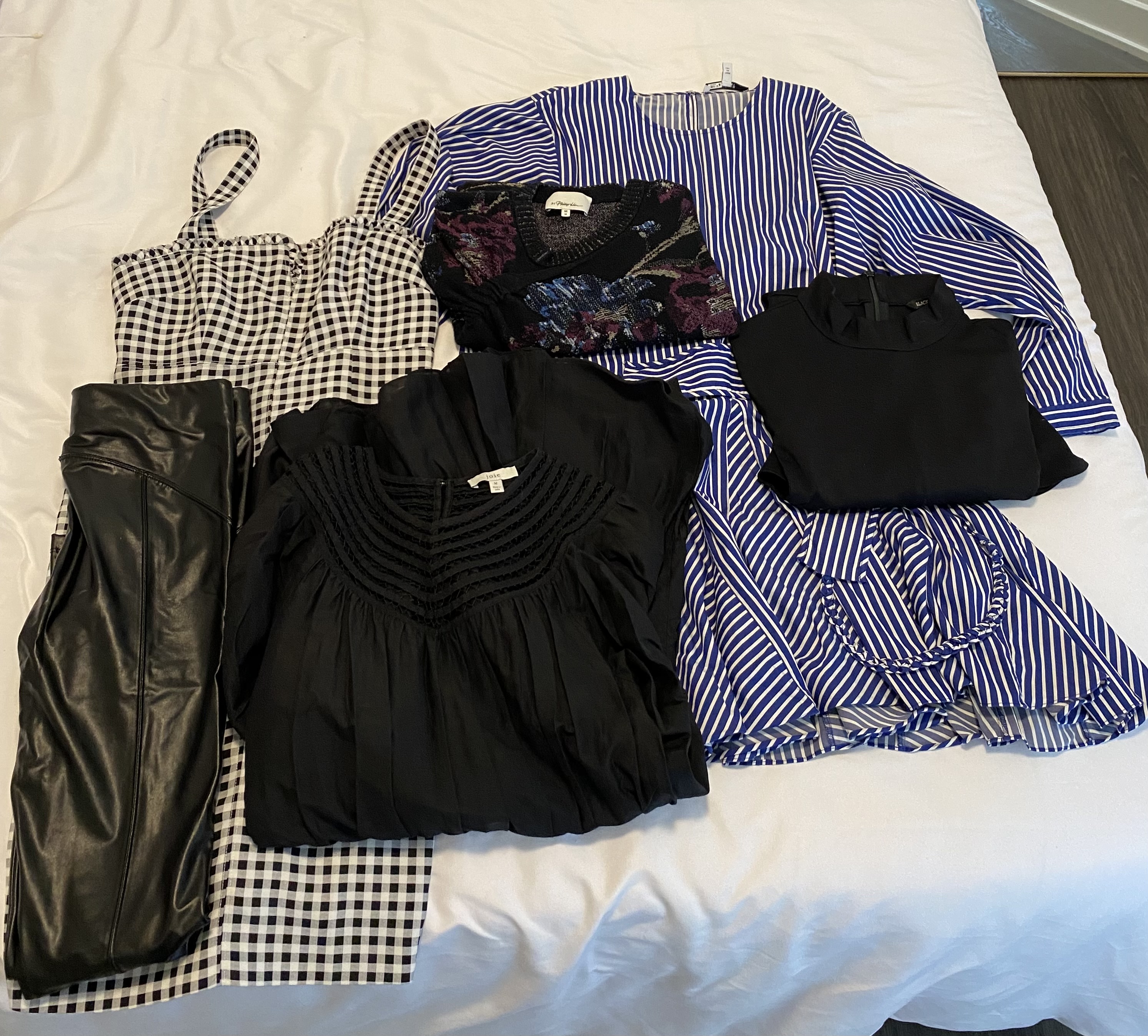 Dresses, pants and tops folded on the bed