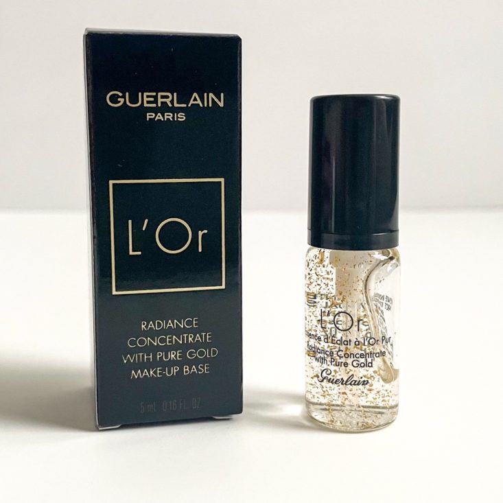 clear primer sample with flecks of gold next to black box it came packaged in