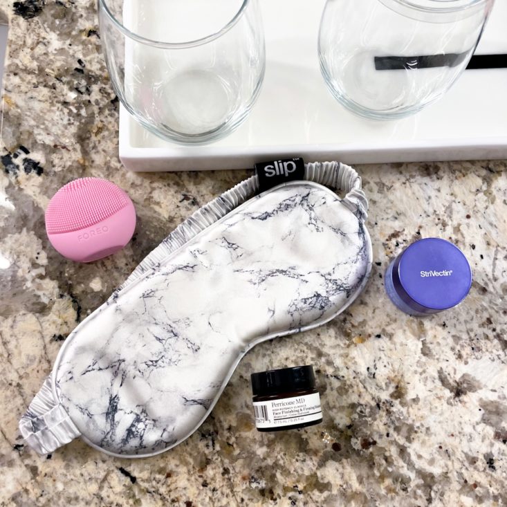 bathroom counter with silk face mask, FOREO cleanser, lip mask, and moisturizer sample