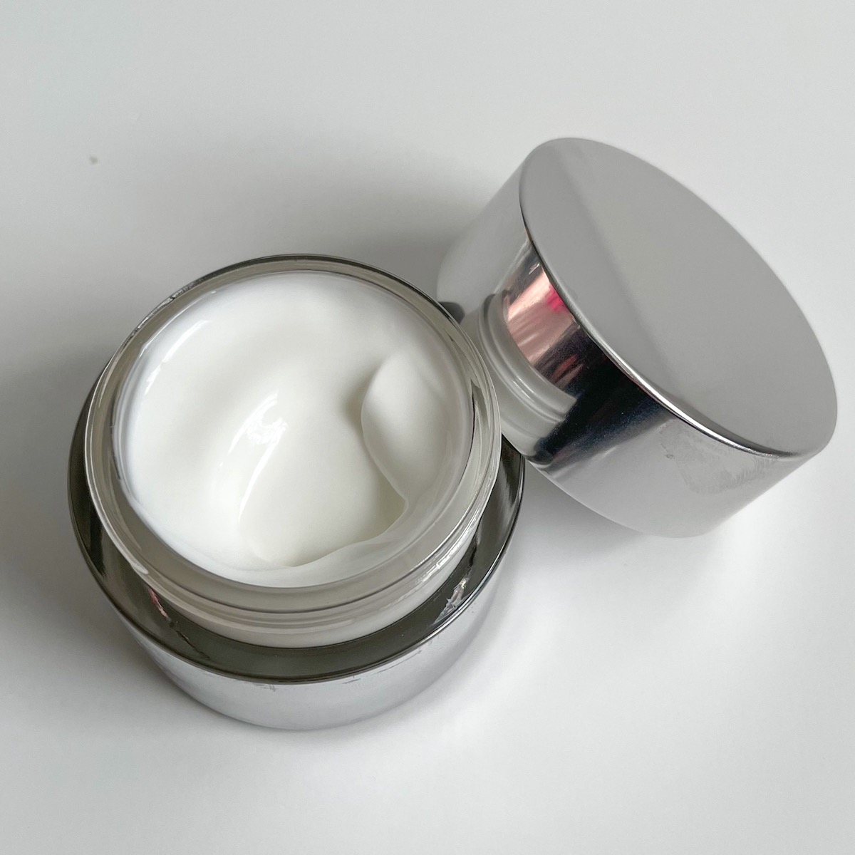 opened silver jar showing white texture of moisturizer