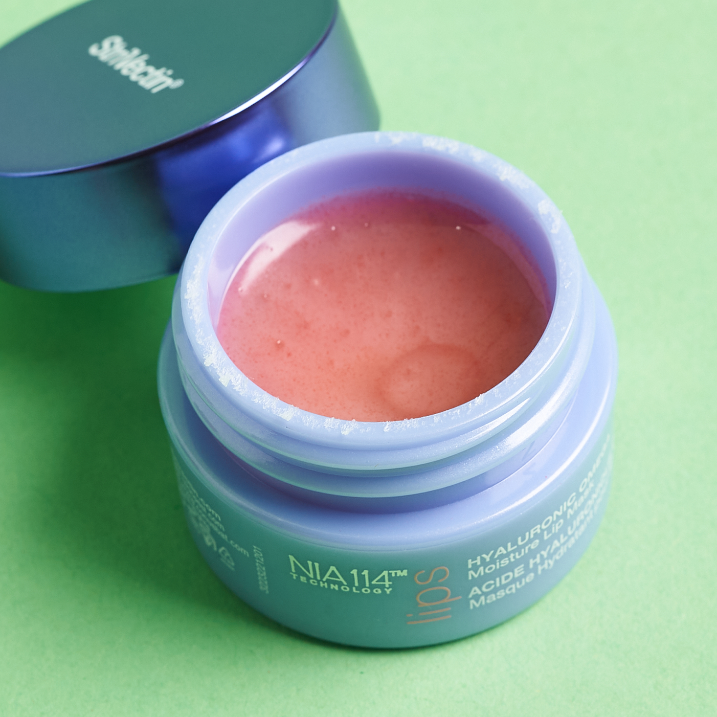 open purple jar showing pink texture of lip mask