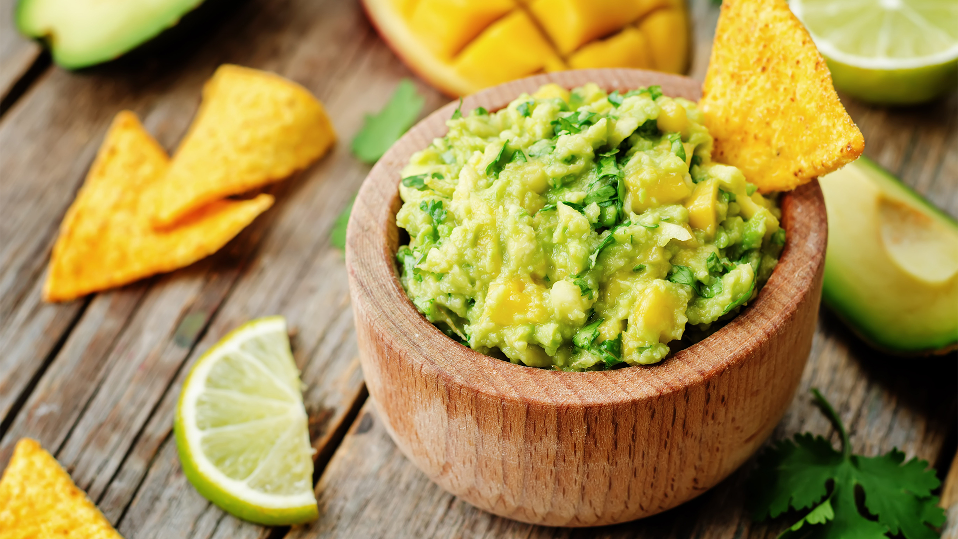 mango guacamole with corn chips on a dark wood background. the toning. selective focus