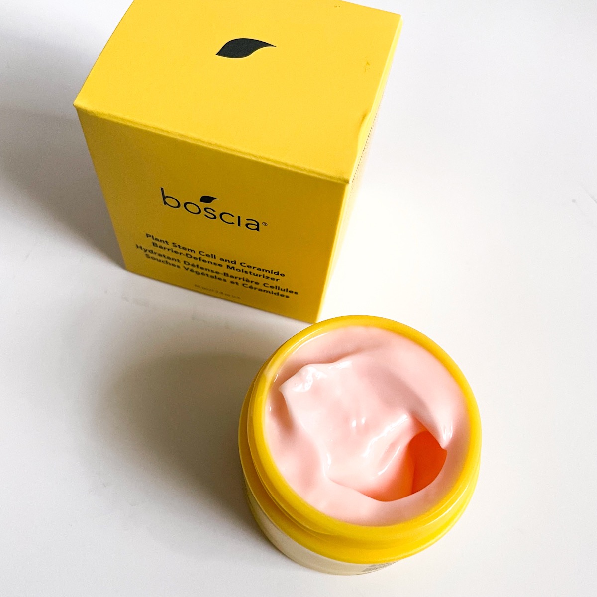 opened jar of moisturizer showing pink texture with yellow box next to it