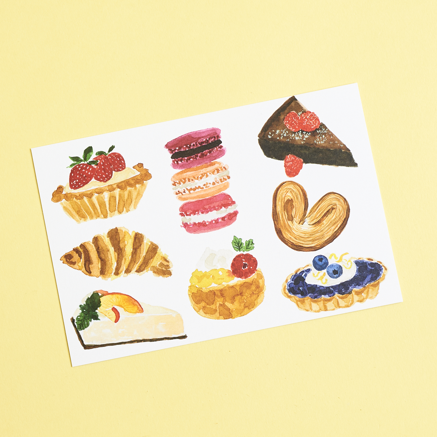 back of info sheet that shows various artwork depictions of food including macarons and a croissant
