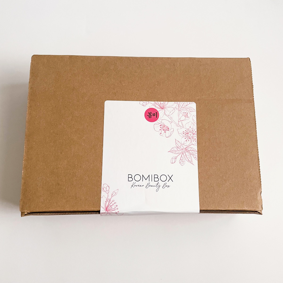 brown box with white and pink bomibox label