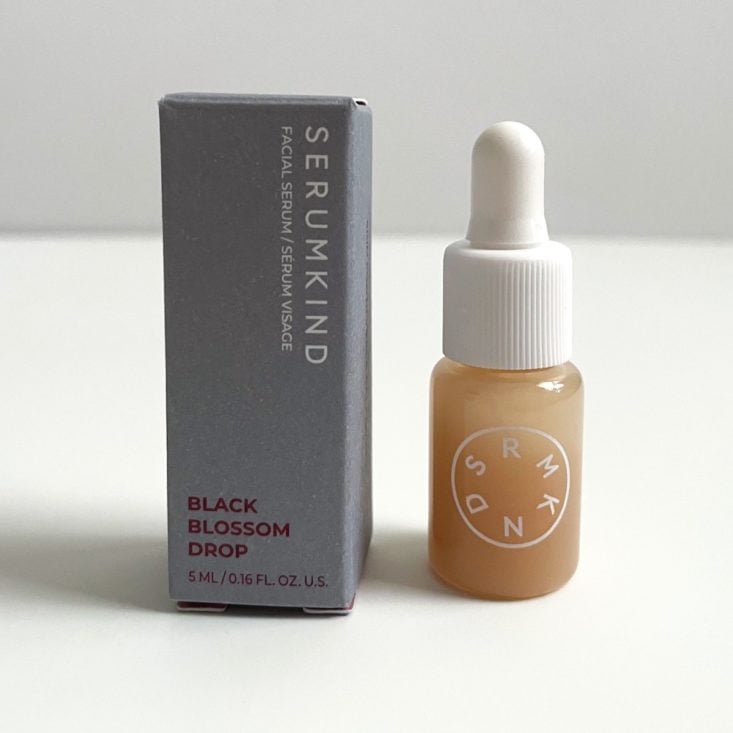 grey box with small bottle of orange serum next to it