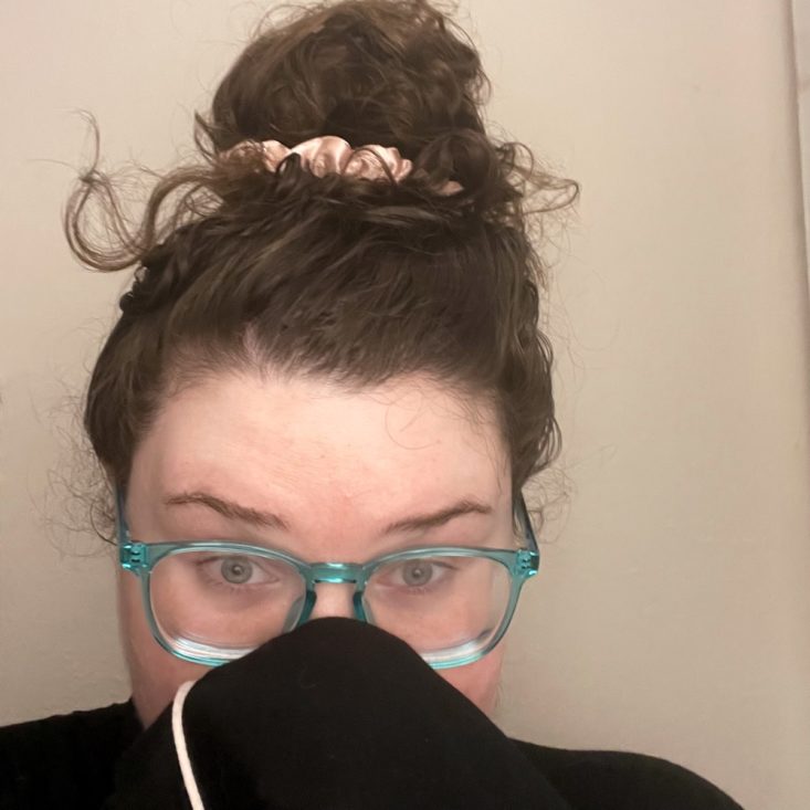 big bun collected by pink scrunchie with stray curls escaping