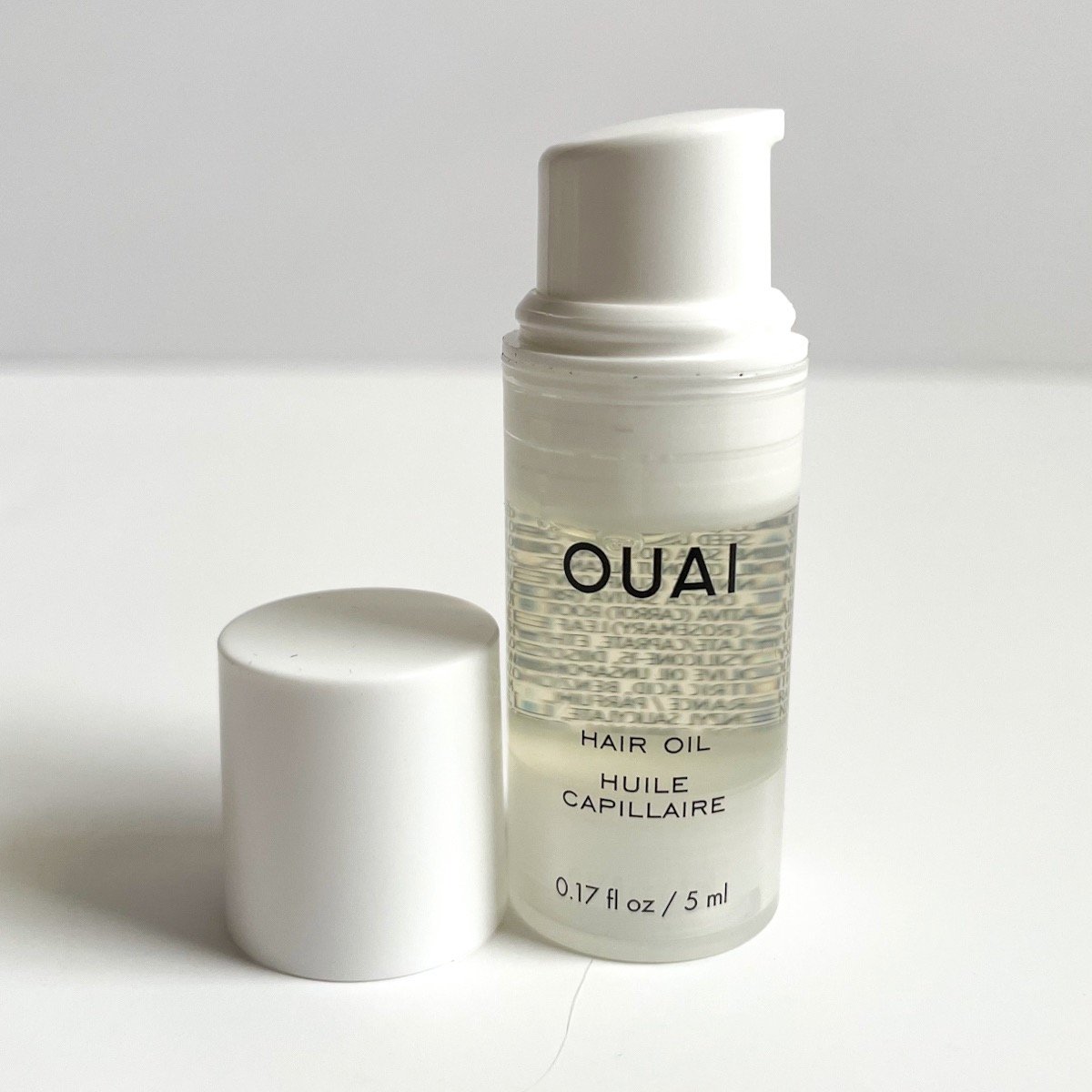 opened bottle of clear hair oil to show white pump top