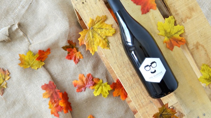 Photo of wine bottle on a wood crate with autumn leaves sprinkled about