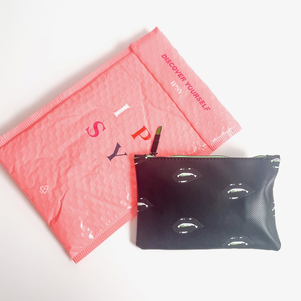 black Ipsy makeup bag with pink bubble mailer