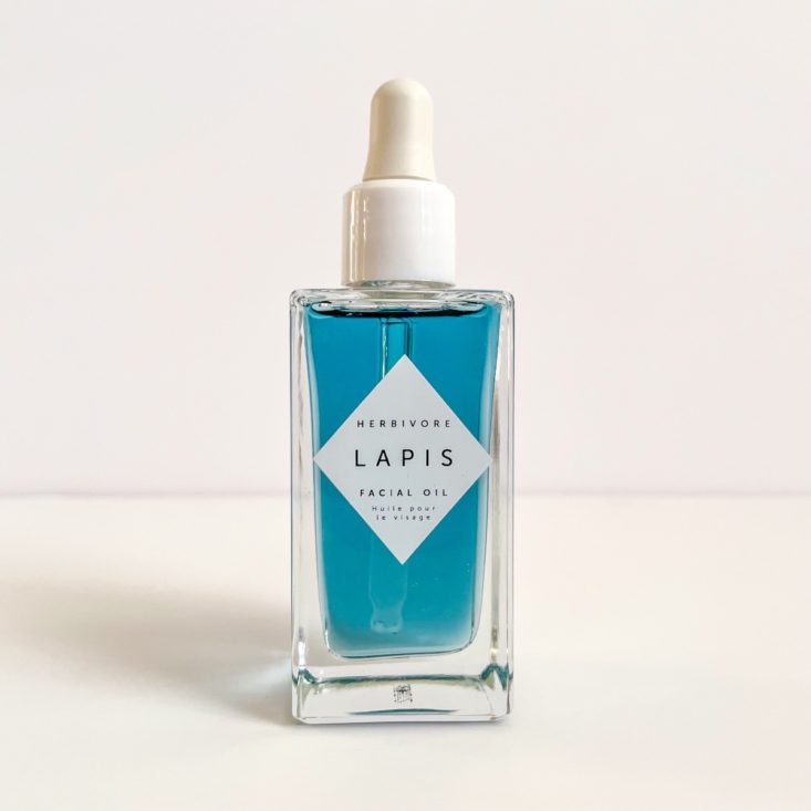 clear glass bottle of blue facial oil