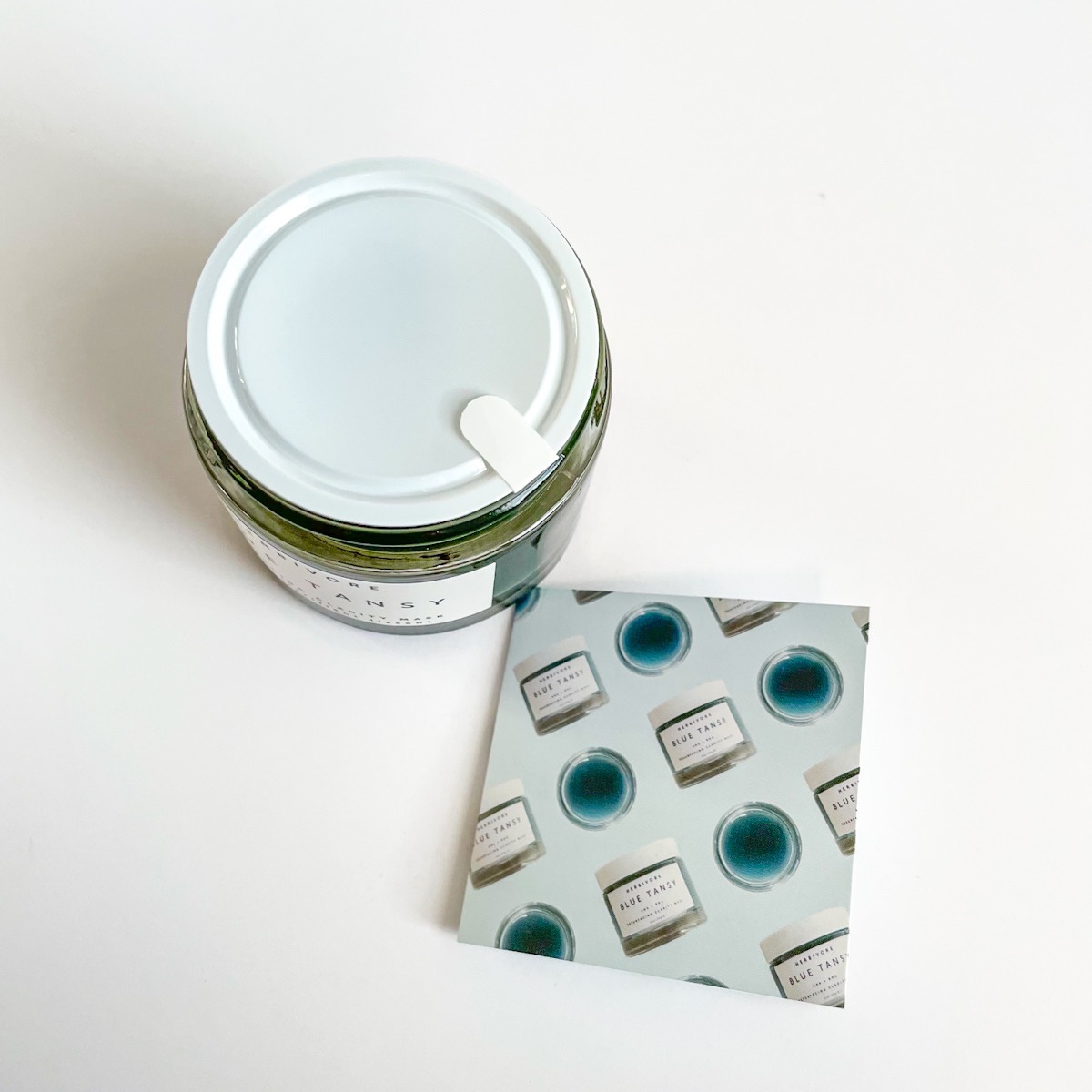 opened jar showing protective film and blue small info sheet that came packaged with mask